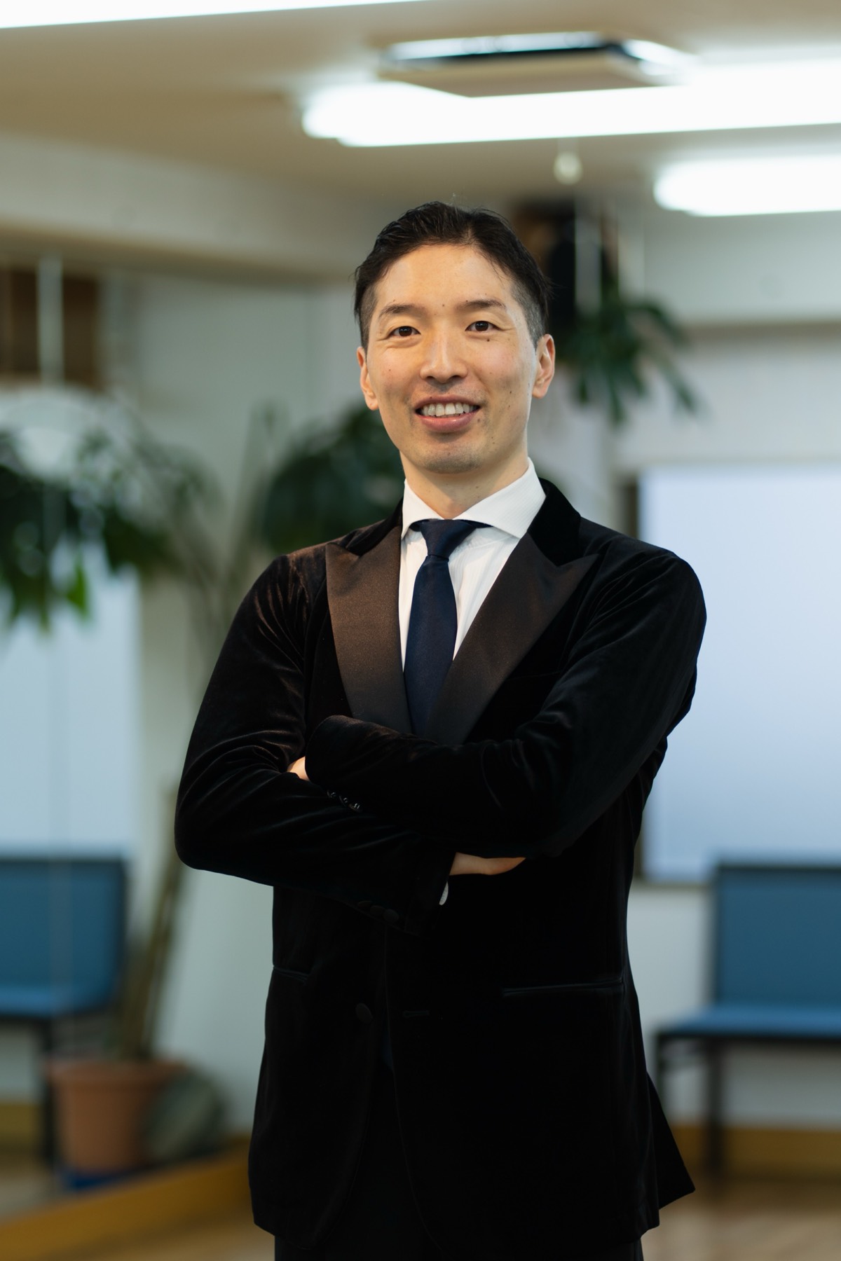 Koji smiling with his arms crossed in the studio